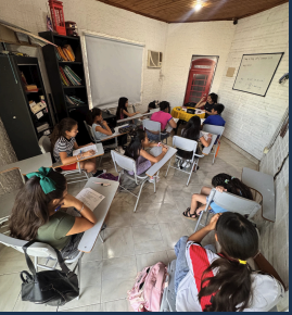 Students in an on-site English class, seated at desks with the teacher at the front of the room.